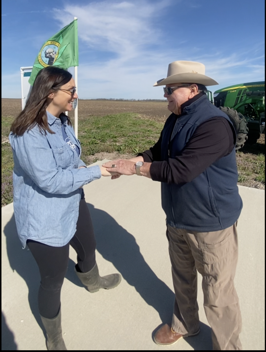 Sarah Stephens and Bill Cook Shake Hands in a Hemp Field During Their Interview on Planting Day